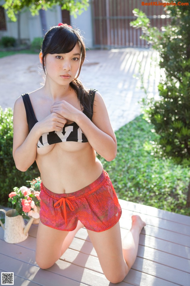 A woman in a black top and red shorts posing for a picture.