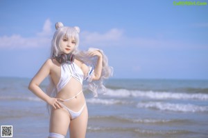 A woman in a white bikini sitting on a beach.