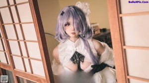 A woman with purple hair wearing a black and white dress.