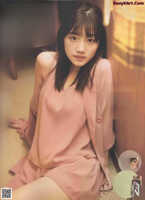 a woman standing in front of a wall wearing a pink blazer