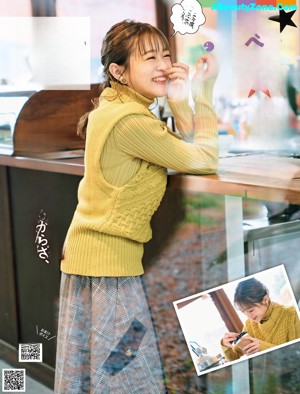 A woman sitting at a table holding a book.