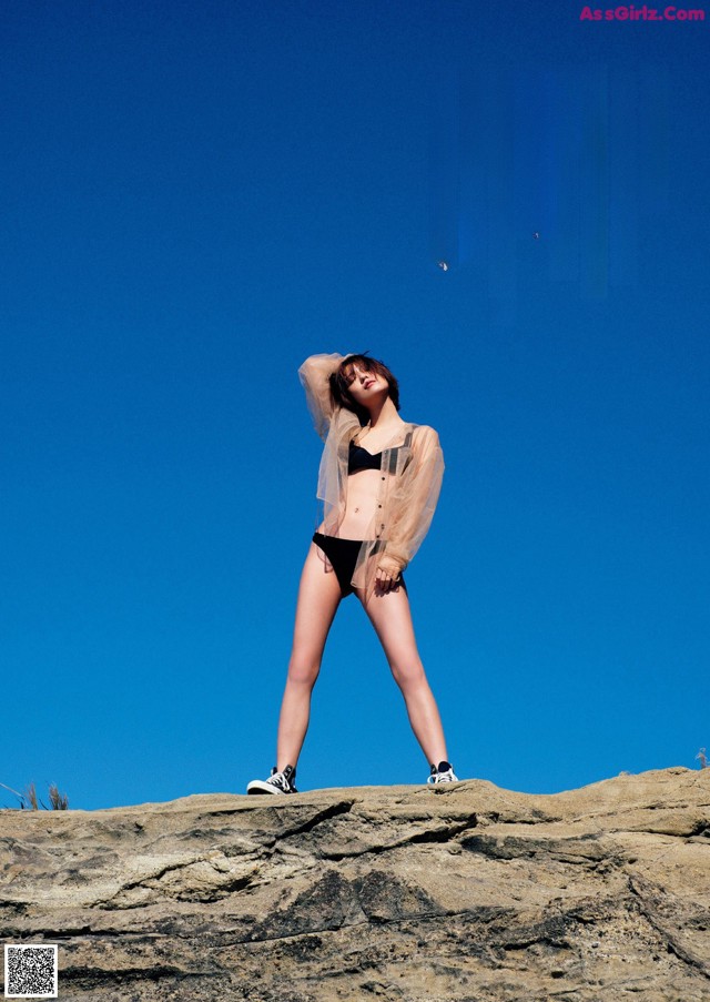 A woman standing on top of a large rock.