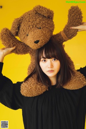 A woman holding a teddy bear in front of a mirror.