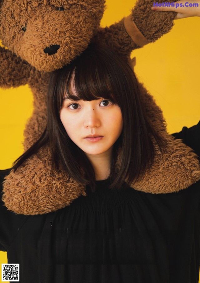 A woman holding a teddy bear on her head.