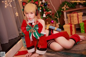 A woman sitting on the floor in front of a Christmas tree.