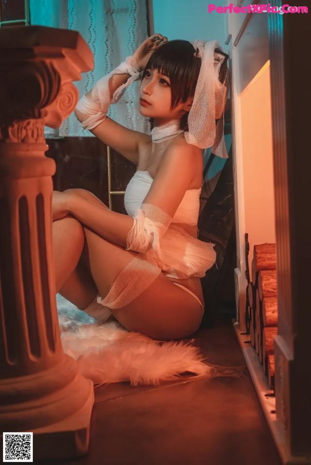 A woman in a white lingerie sitting on the floor.