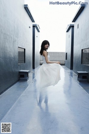 A woman in a white dress standing on a roof.