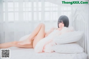 A woman sitting on top of a white bed.