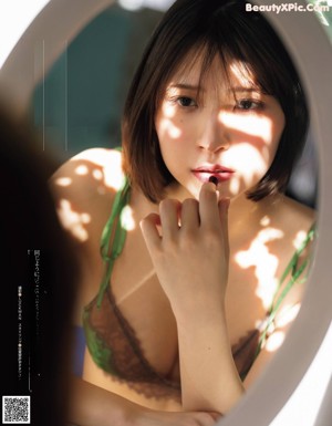 A woman in a green lingerie sitting on a chair.