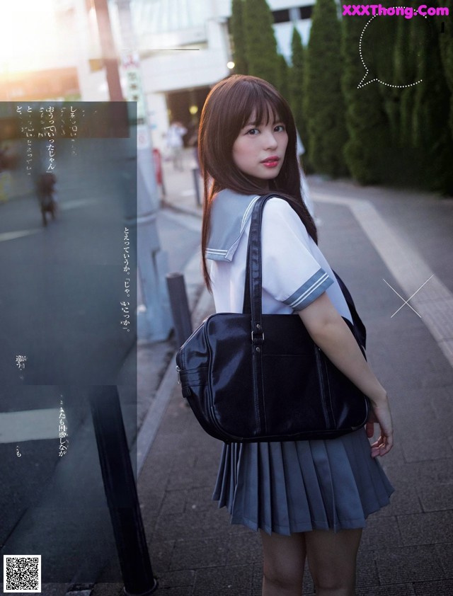 A woman in a school uniform is holding a black bag.