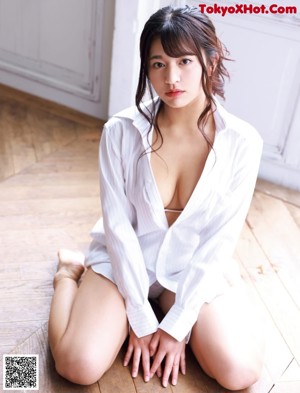 A woman in a white shirt is sitting on the floor.