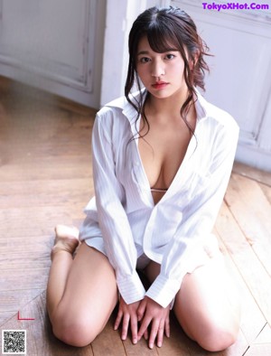 A woman in a blue bikini leaning against a wall.