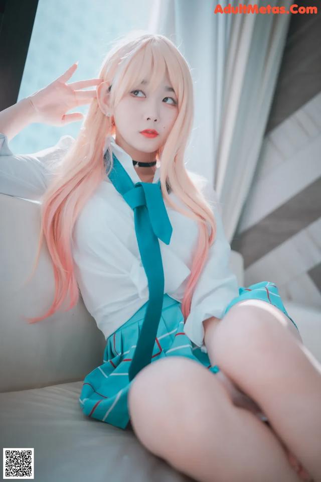 A woman with long pink hair sitting on a couch.