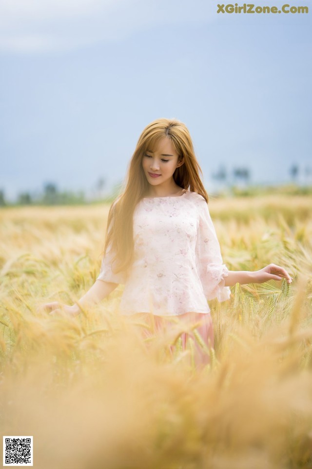 A woman standing in a field of wheat.