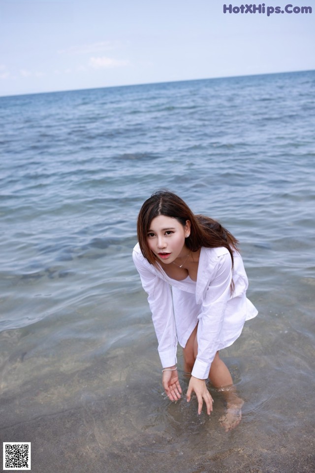 A woman in a white shirt is standing in the water.