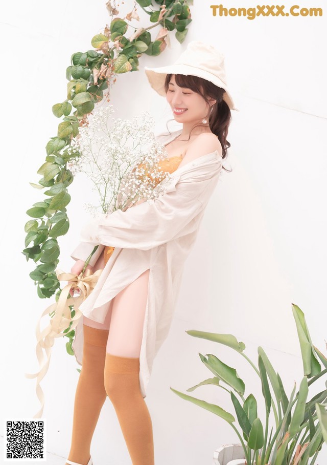 A woman in a white shirt and yellow stockings holding a bouquet of flowers.