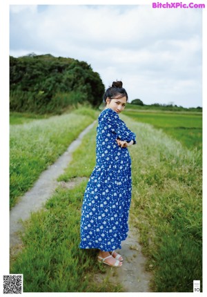 A woman in a blue dress making a peace sign with her hands.