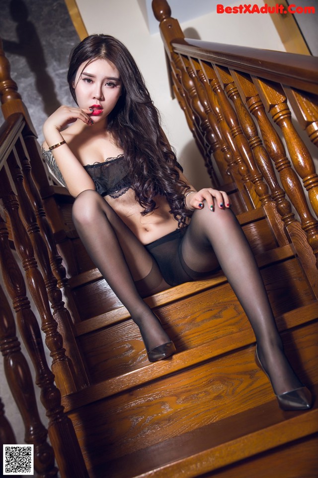 A woman in black stockings sitting on a wooden staircase.