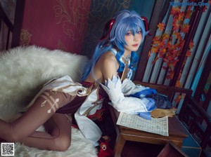 A woman with blue hair is sitting on a white rug.