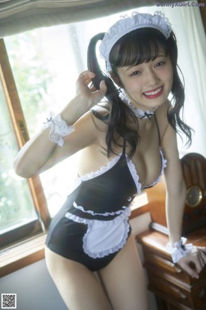 A woman in a maid outfit sitting on a chair.