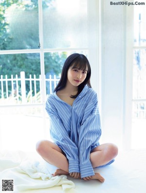 A woman sitting on top of a bed with her legs crossed.