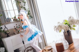 A woman in a blue and white maid outfit holding a broom.