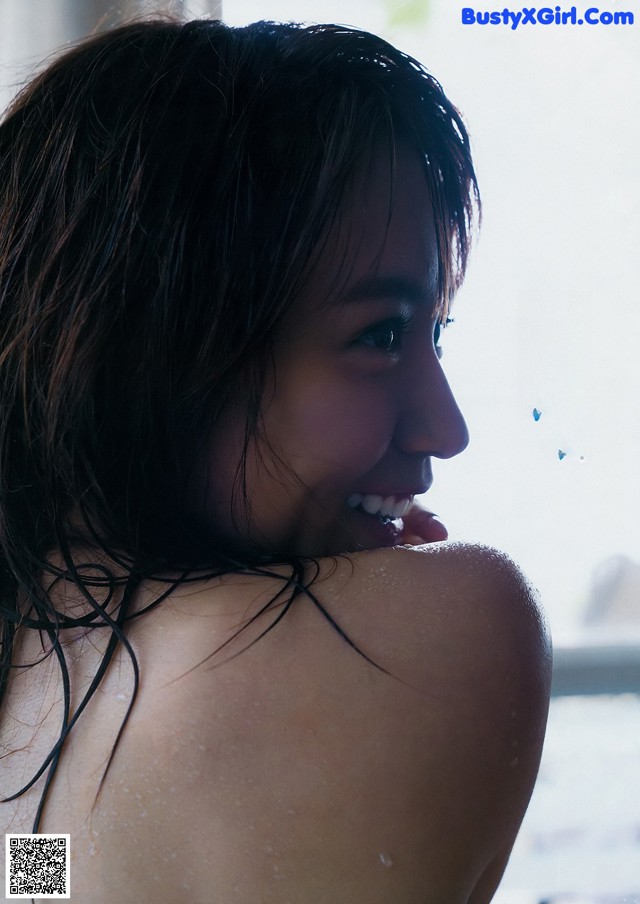 A woman with wet hair standing in front of a window.