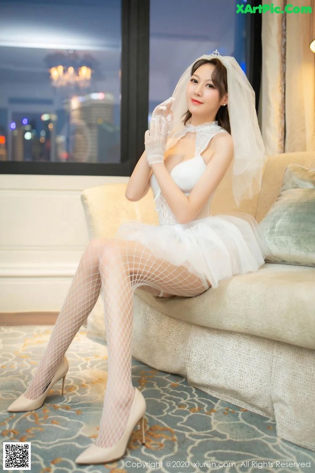 A woman in a wedding dress sitting on a couch.