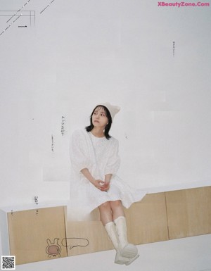 A woman in a white sweater is posing for a magazine.