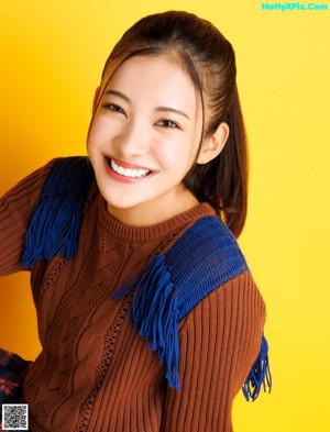 A woman in a brown sweater smiles at the camera.