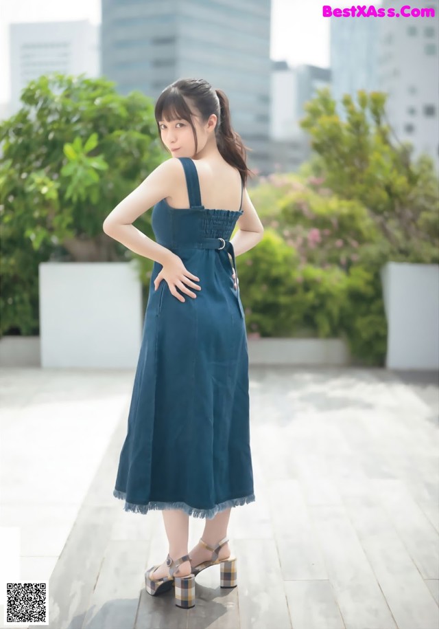 A woman in a blue dress standing on a wooden floor.