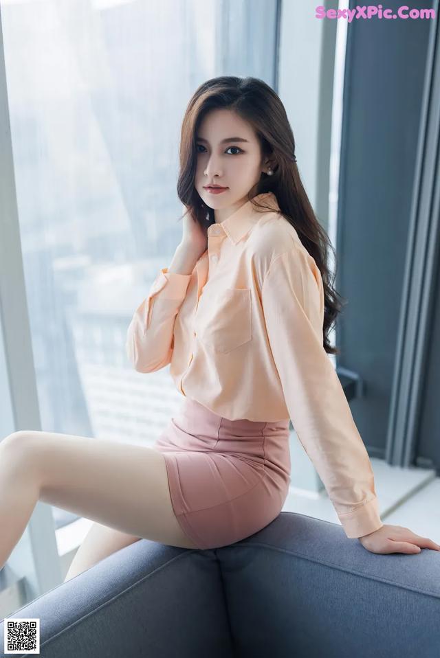A woman sitting on top of a couch next to a window.