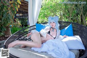 A woman with blue hair sitting on a lounge chair.