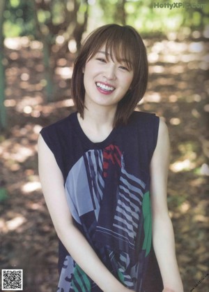 A woman in a white shirt sitting on a beach.