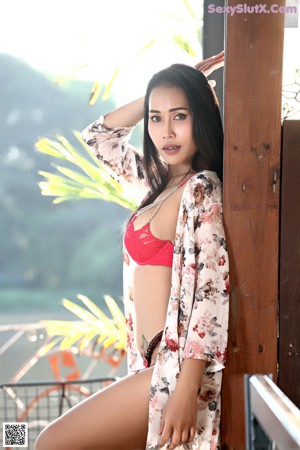 A woman in a red and black lingerie posing for the camera.