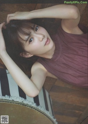 A woman with long brown hair leaning against a wall.