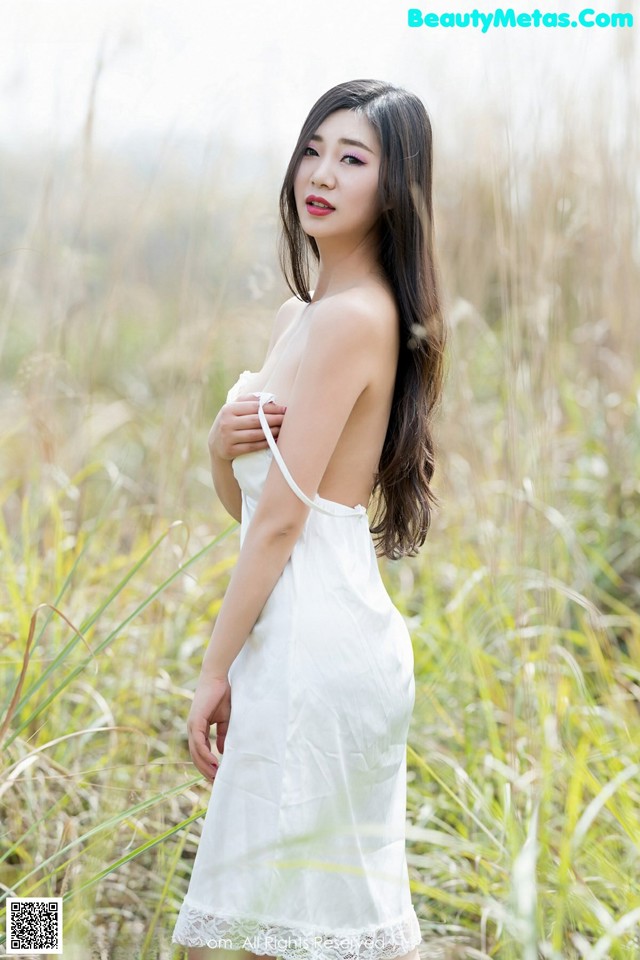 A woman in a white dress standing in tall grass.