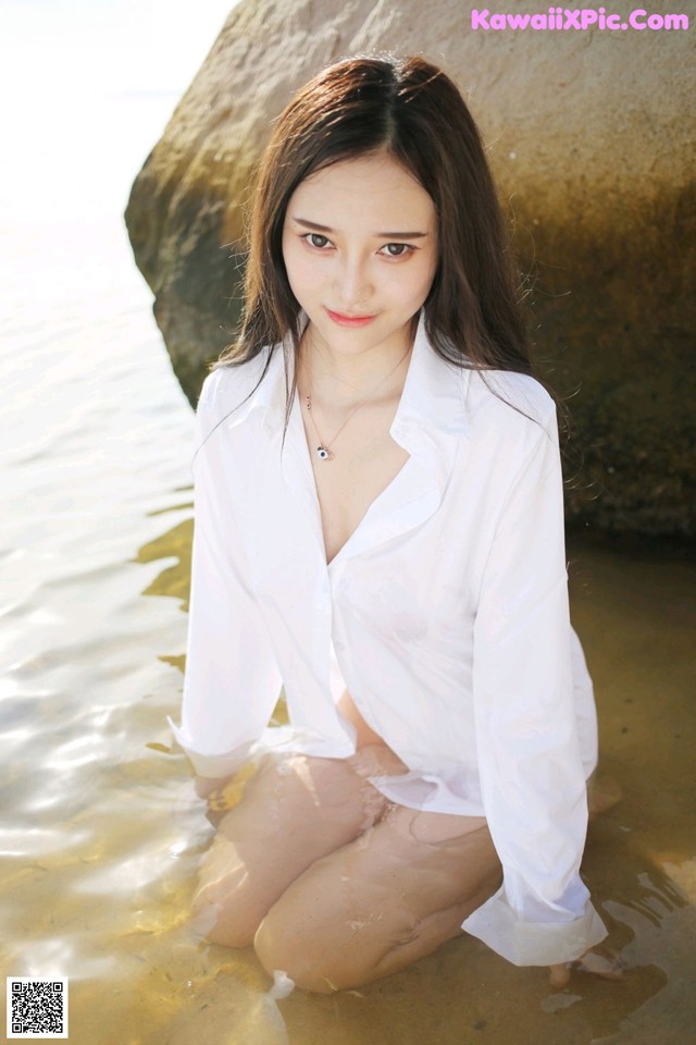 A woman in a white shirt sitting in the water.