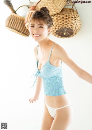 A woman in a gray tank top holding a blue and white towel.