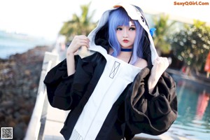 A woman with blue hair sitting on the edge of a pool.