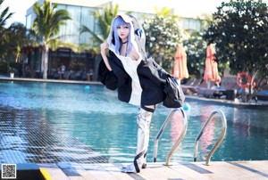 A woman with blue hair sitting next to a swimming pool.