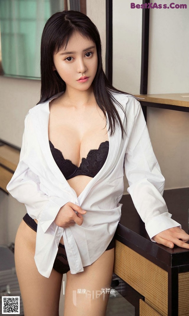 A woman in a white shirt and black panties posing for a picture.