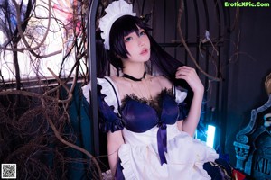 A woman in a maid outfit sitting on a couch.