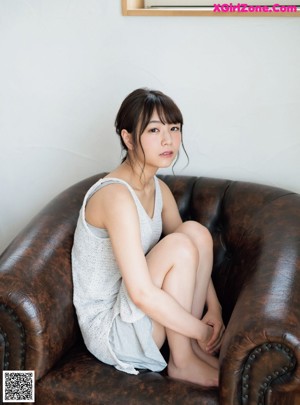 A young woman laying on a bed with her hand on her chin.