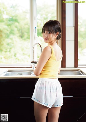 A young woman in a pink panties leaning against a wooden pole.
