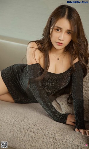 A woman sitting on the floor in front of a bathtub.