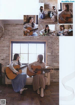 A woman standing in front of a window next to a guitar.