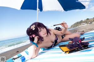 A woman in a bikini sitting on a boardwalk next to the ocean.