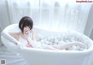 A woman in a white dress sitting in a bathtub.