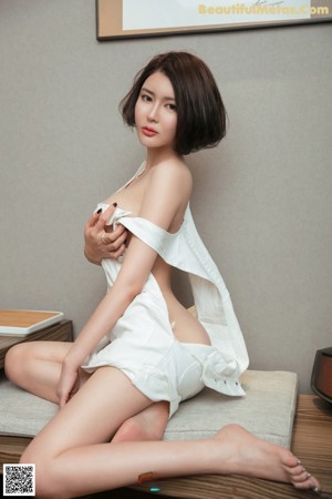 A woman in a white dress sitting on a wooden bench.